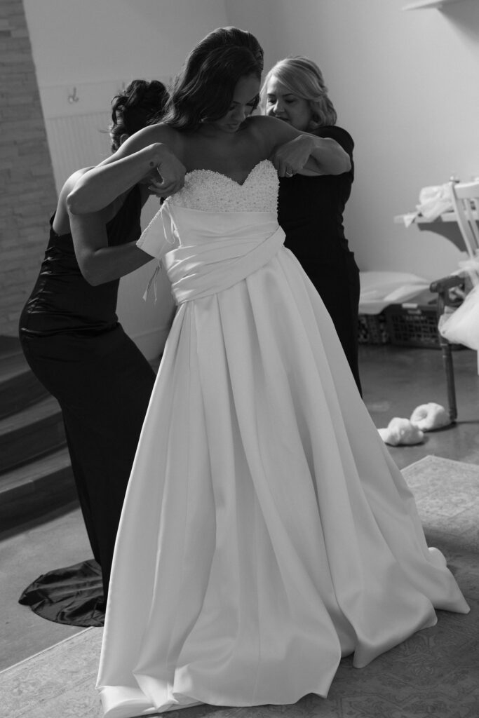 bride putting on her wedding dress with her parents helping her