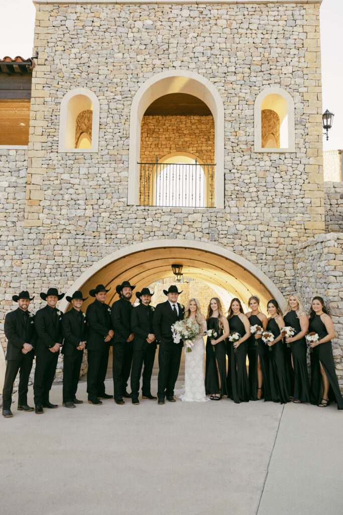 wedding party photos, bride and groom in the middle with bridesmaids and groomsmen on the sides wearing all black