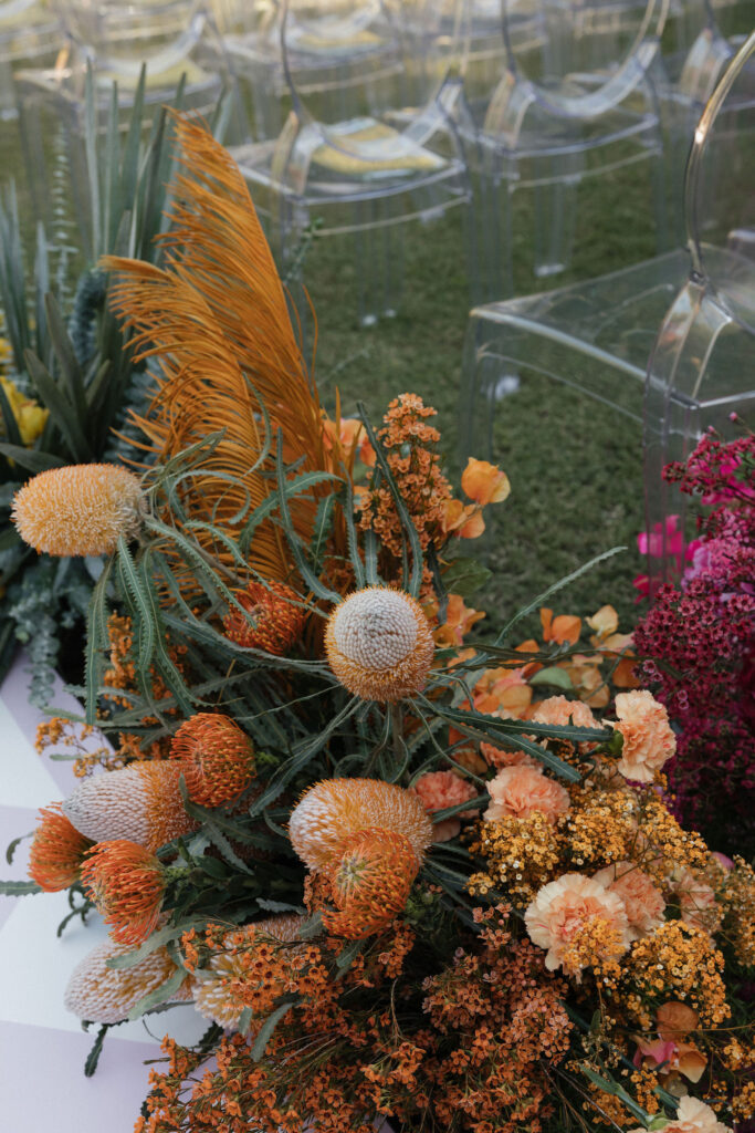 A close-up of rustic floral decorations featuring orange and peach flowers with unique textures, creating a warm and earthy look.