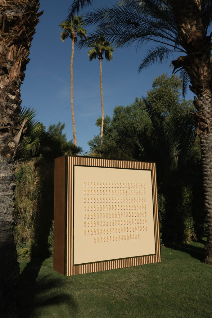 A display wall featuring custom keychains with orange tassels for wedding guests, labeled with names.