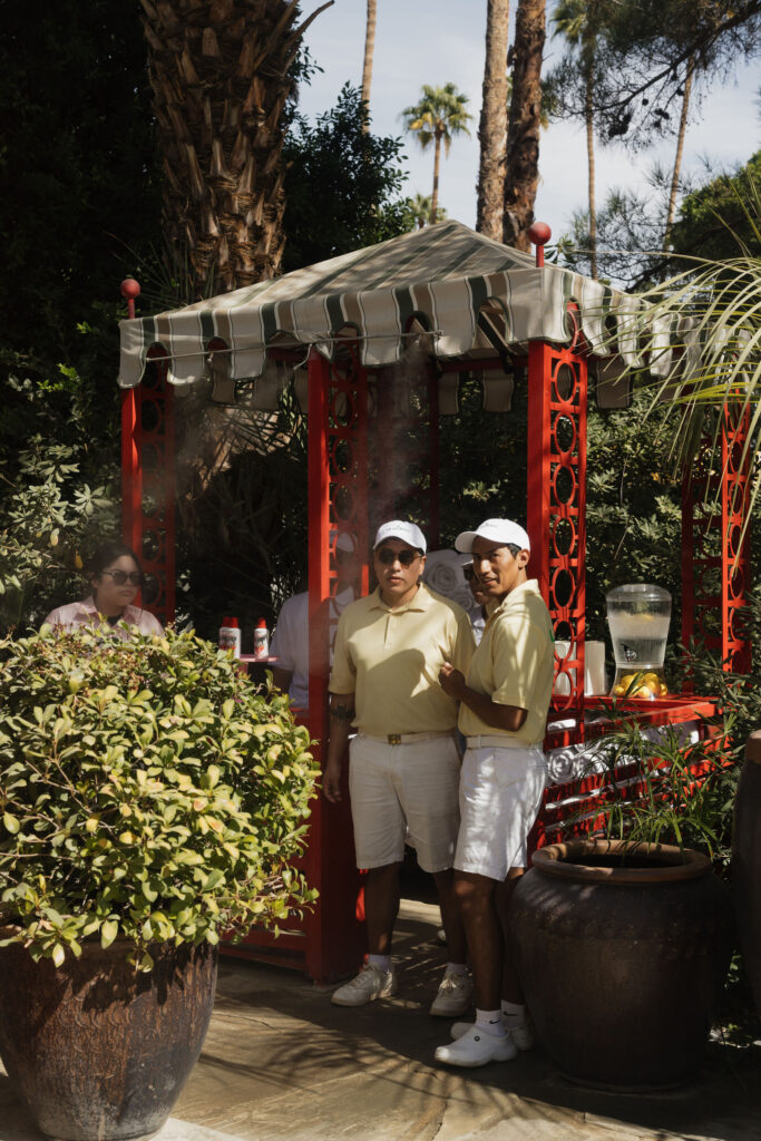 Two staff members in yellow shirts and caps stand beside a red gazebo, ready to assist guests during the outdoor celebration at Park Palm Springs Hotel.