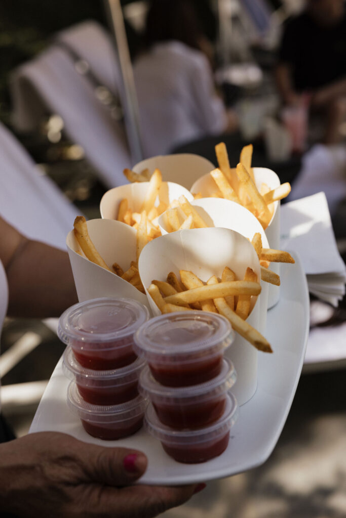 French fries with ketchup - A tray of cone-shaped containers filled with French fries, served with small containers of ketchup, ready for guests to enjoy.