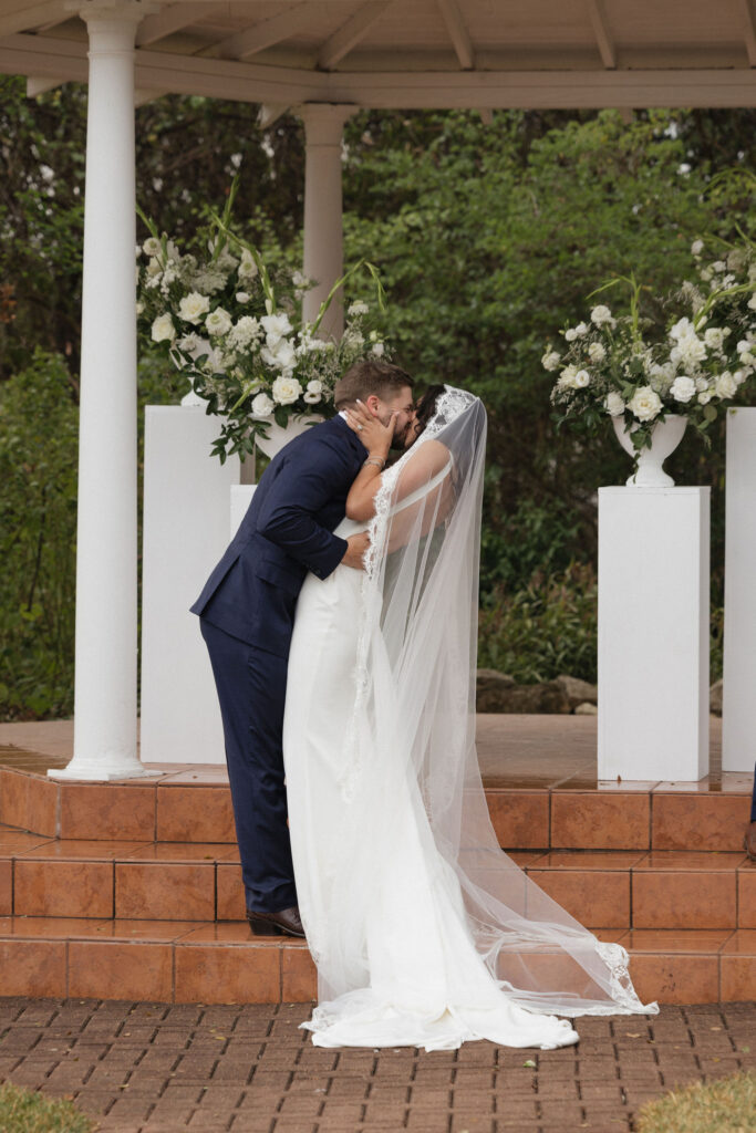  The bride and groom share their first kiss as a married couple in front of their guests at the outdoor ceremony space of The Winfield Inn.