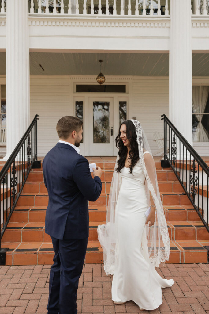 A bride and groom share an emotional moment during their first look, standing on the brick steps of The Winfield Inn's charming white-columned porch.