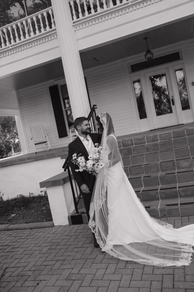 A formal portrait of the couple standing on the steps of The Winfield Inn’s iconic white-columned facade, showcasing timeless elegance.