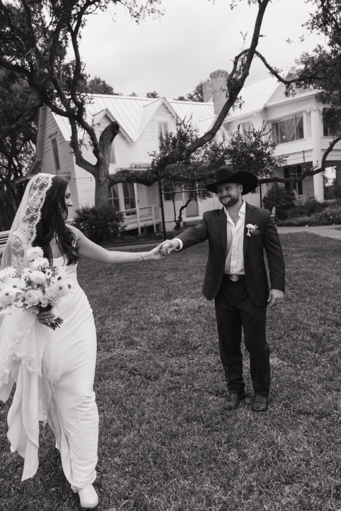 A black-and-white image of the bride and groom sharing a dance on the lush lawn of The Winfield Inn, the historic house serving as the backdrop.