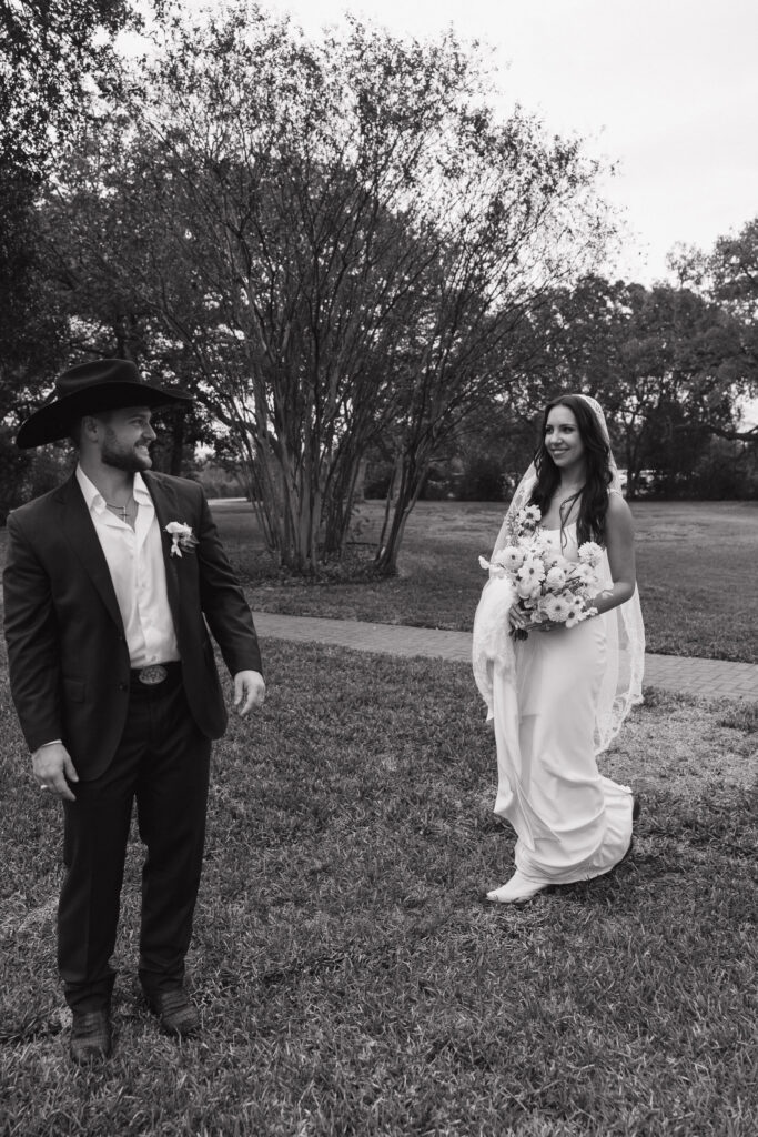 The bride and groom approach each other with joyful anticipation on the lawn of The Winfield Inn, surrounded by serene greenery.