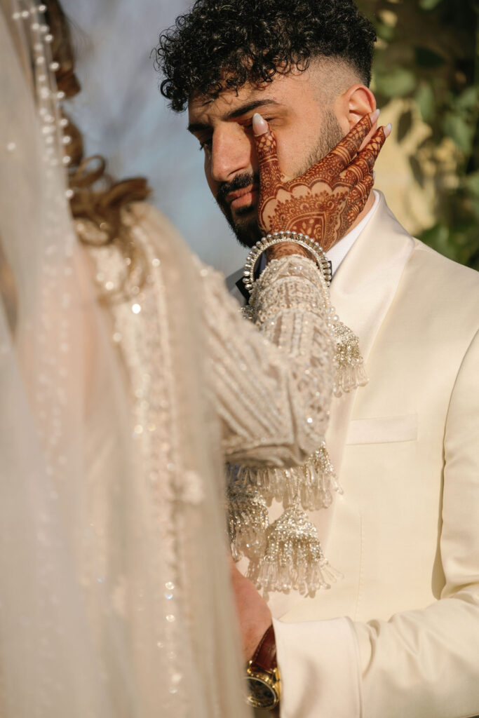 The bride wiping a tear from the grooms eyes during their wedding ceremony