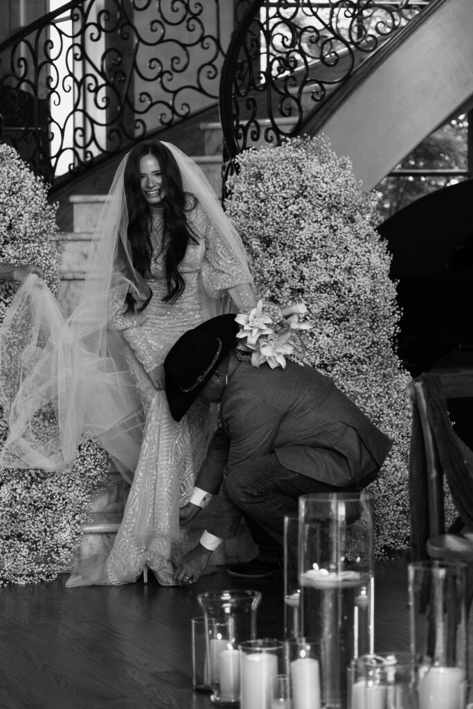 father of the bride putting her heels on his daughters feet before walking her down the aisle