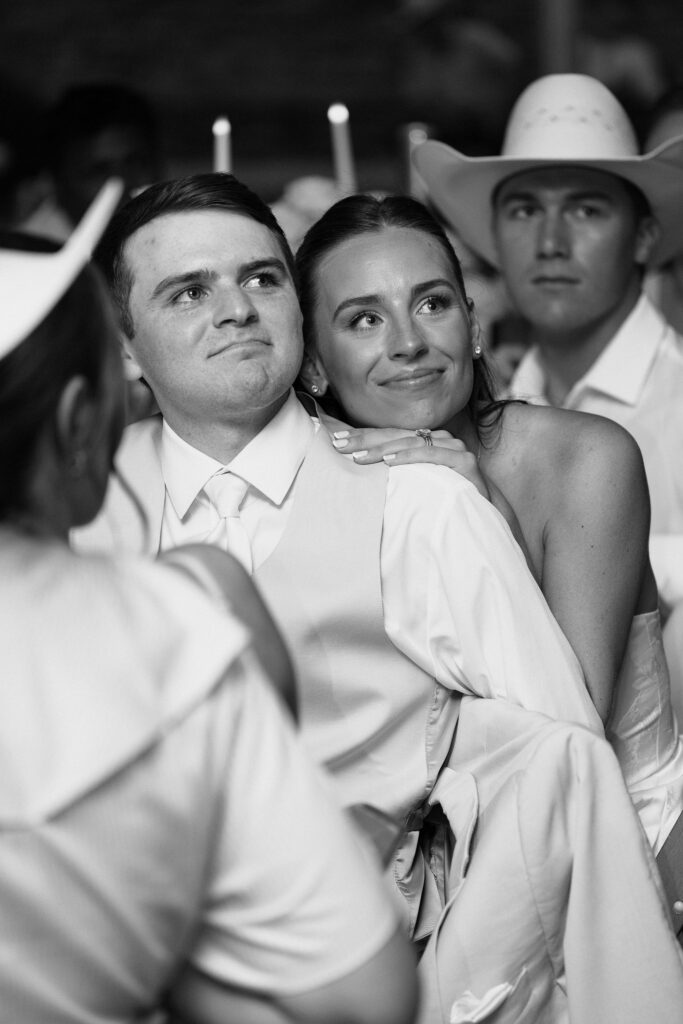 bride and groom smiling at wedding while seated