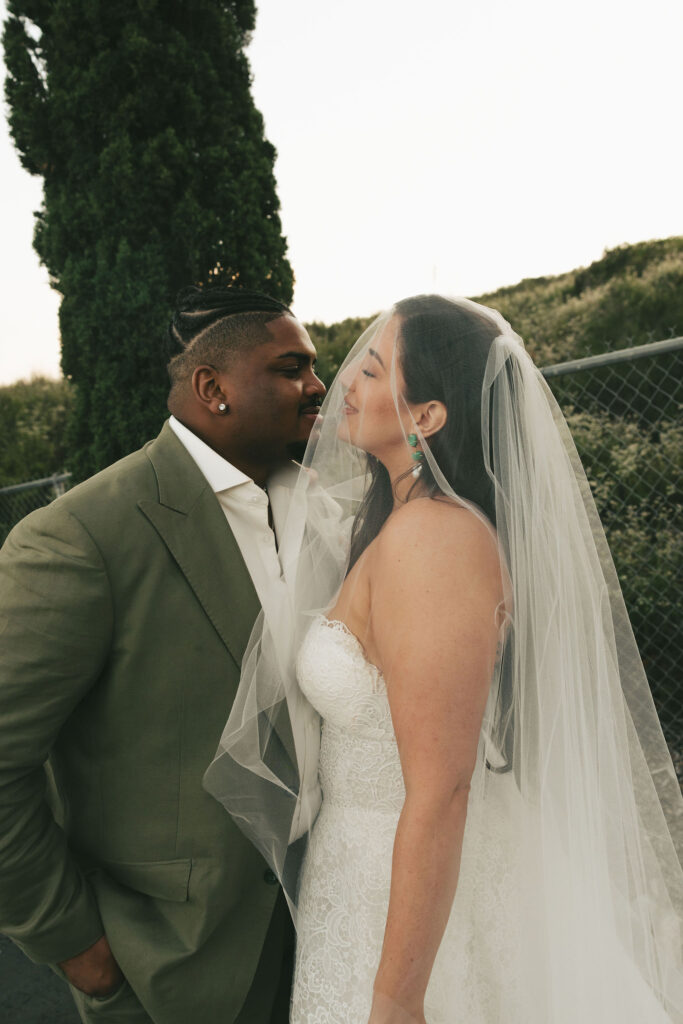 bride with long veil smiling at groom in san diego