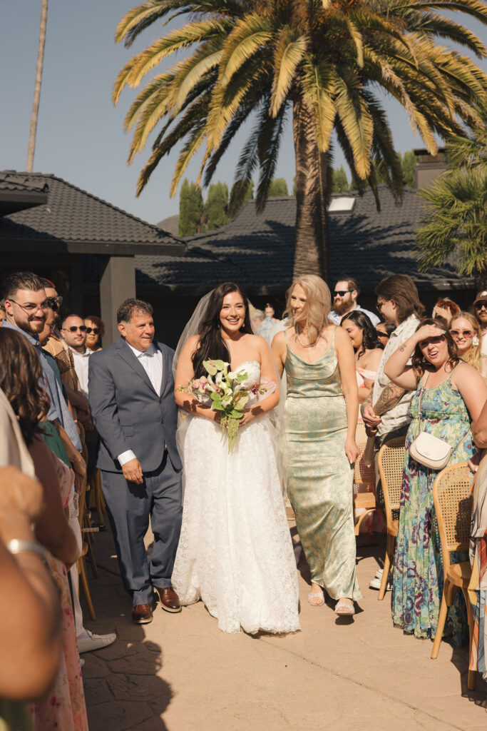 bride walking with parents to wedding ceremony