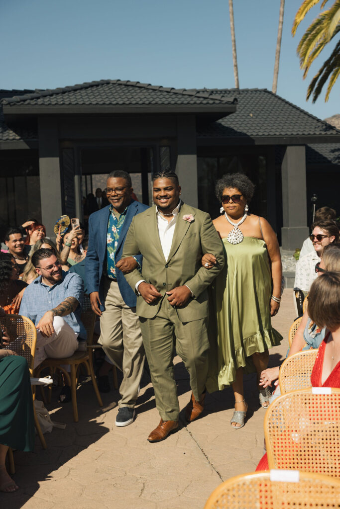 groom walking to wedding ceremony with parents