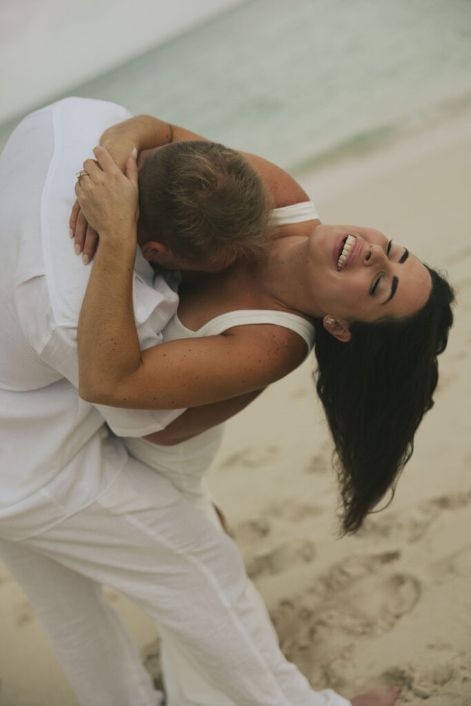 bride laughing with groom on beach
