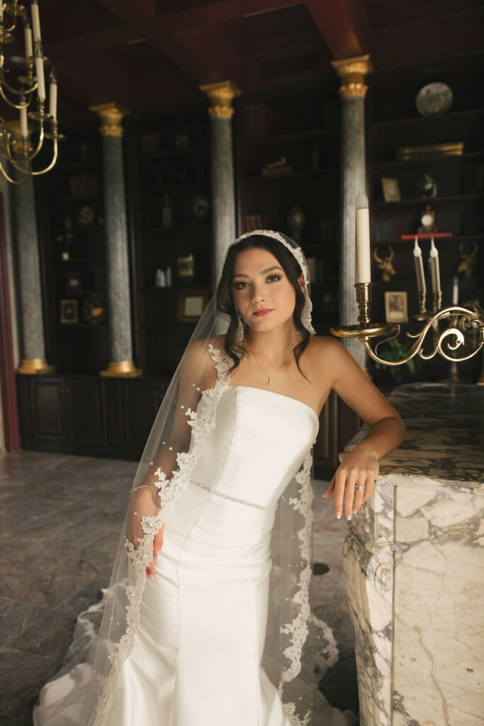 bride leaning on marble counter in wedding dress