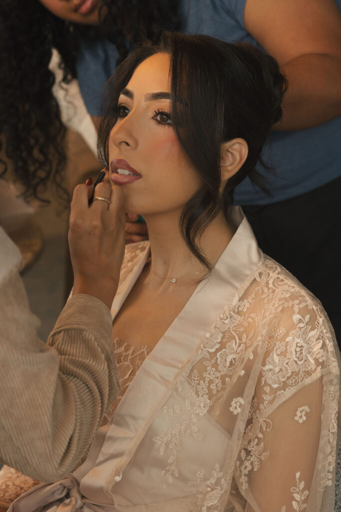 bride getting makeup done on wedding day
