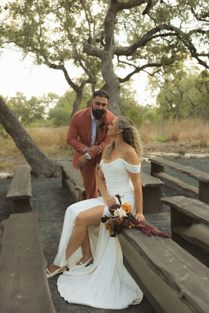 bride on bench with groom during fall wedding at the cedars ranch