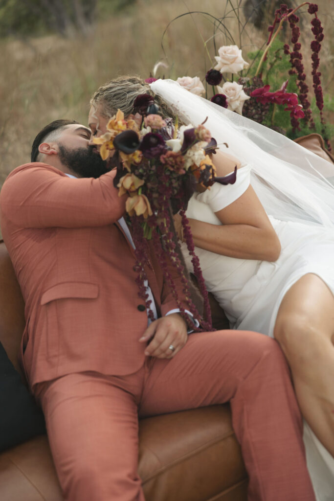 bride and groom kiss behind flowers at the cedars ranch